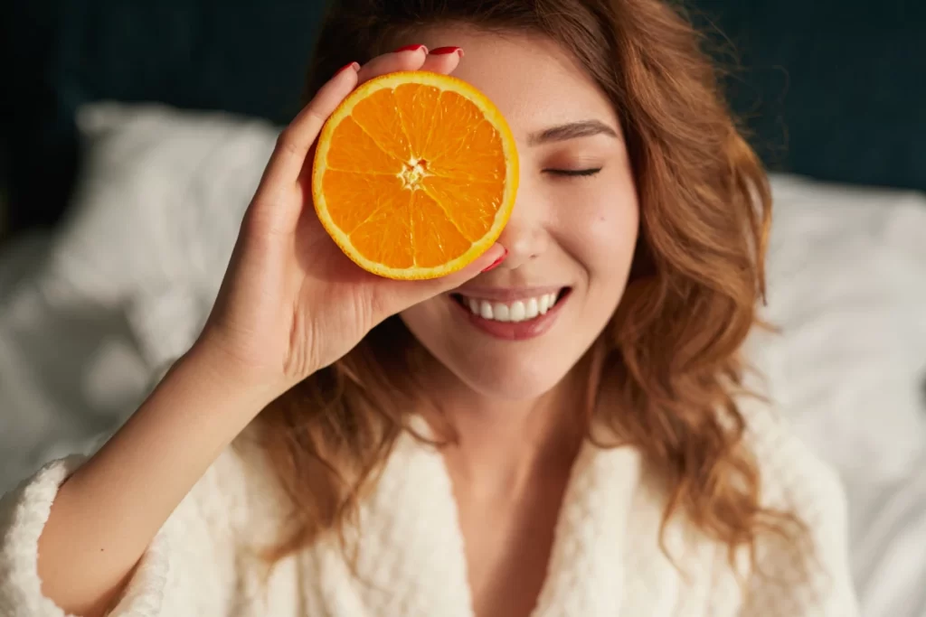 Femme rayonnante tenant une orange devant son visage