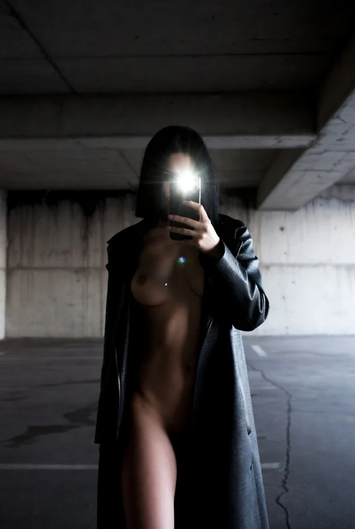 Selfie téléphone dans parking, femme ouvrant sa robe pour montrer son corps nu