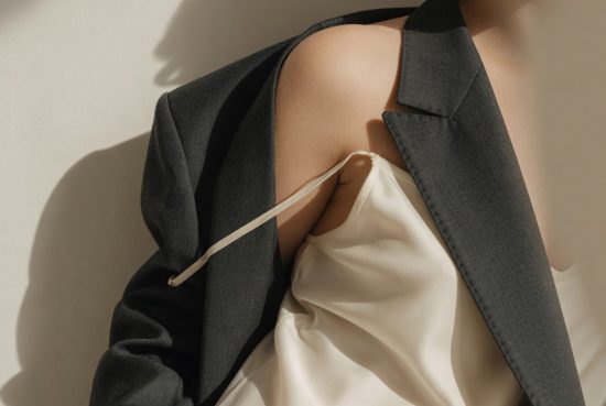 Femme sans visage portant robe soie crème et blazer laine taupe, détail épaule éditorial mode.