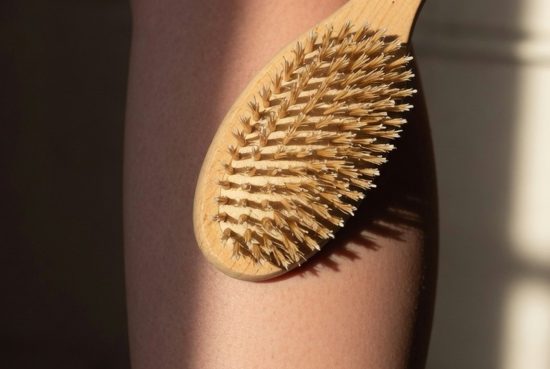 hero Femme en salle de bain appliquant une brosse naturelle sur son mollet nu, mouvement léger ascendant